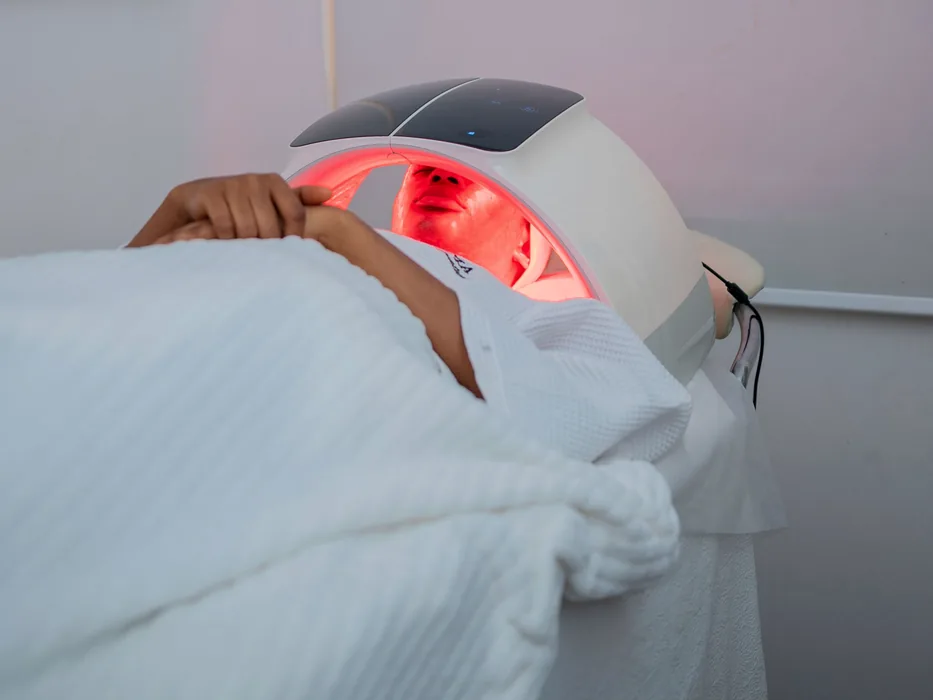 A guest relaxing under a red light panel during a treatment